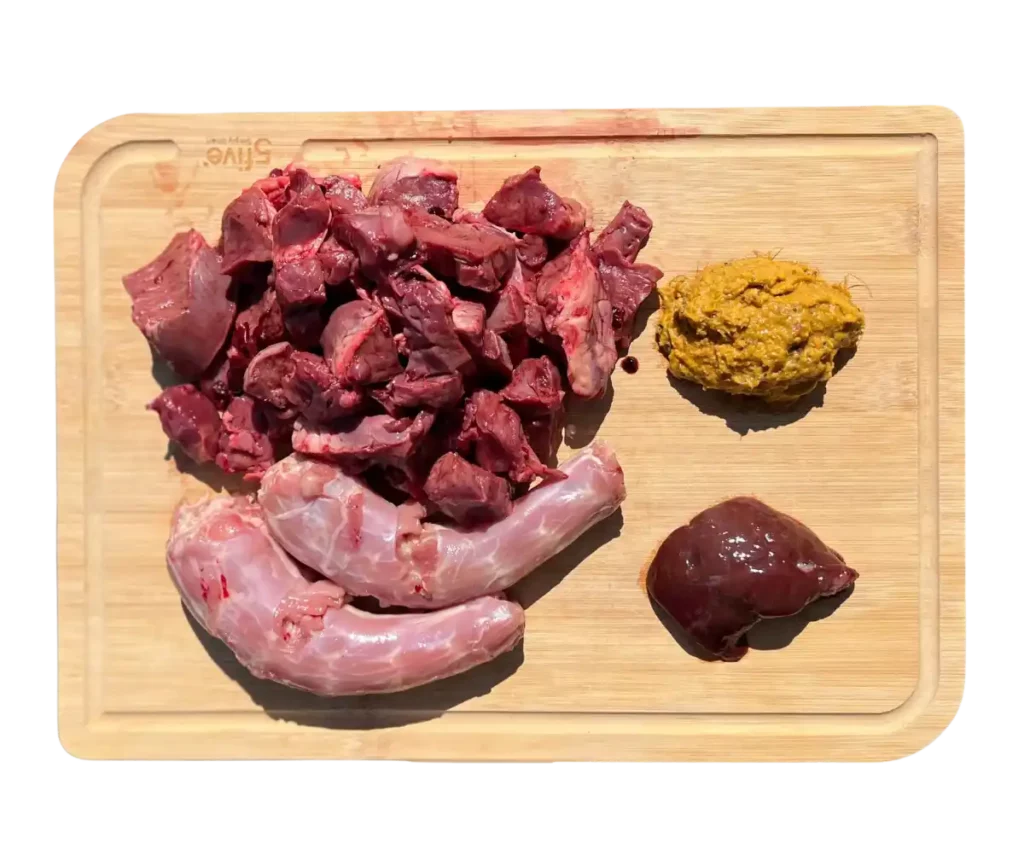 Plateau de BARF pour chien contenant des abats filtrants, des os charnus et des compléments alimentaires.