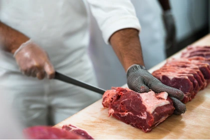 Homme qui découpe de la viande pour du BARF industriel